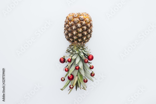 Fotografie, Obraz top view of red christmas balls on fresh pineapple isolated on white