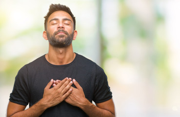 Wall Mural - Adult hispanic man over isolated background smiling with hands on chest with closed eyes and grateful gesture on face. Health concept.