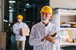 © Dusan Petkovic - Picture of mature male manager with helmet on is head standing in warehouse with tablet in his hands. Looking away.