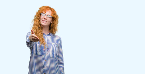 Poster - Young redhead bussines woman smiling friendly offering handshake as greeting and welcoming. Successful business.