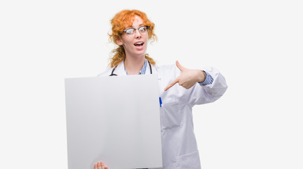 Poster - Young redhead doctor woman holding banner very happy pointing with hand and finger