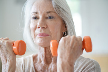 Wall Mural -  Portrait of attractive senior woman exercising with weights