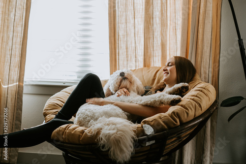 Photographie Girl holding her dog on comfy chair