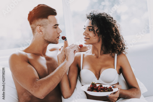 Fototapeta na szkło Szczęśliwa romantyczna para je Strawberrys w łóżku