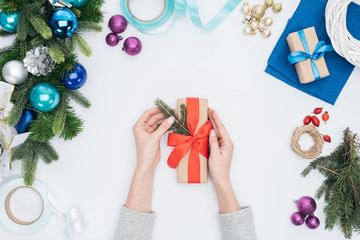 Wall Mural - partial view of woman decorating christmas present with pine tree branch isolated on white