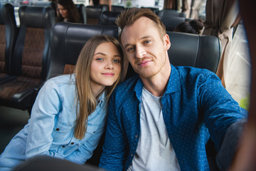 Wall Mural - adult happy man taking selfie with beautiful girlfriend during trip on travel bus