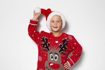 Cute little boy in Christmas sweater and hat on white background