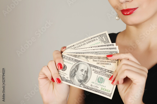 Fotografía Women holds a pile of money on a gray background.