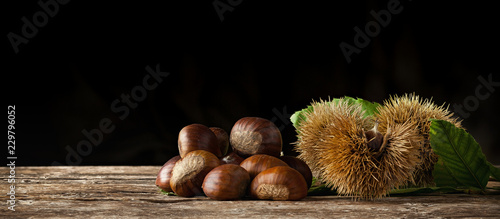 Fotomural Chestnuts and chestnut bur on wooden table.