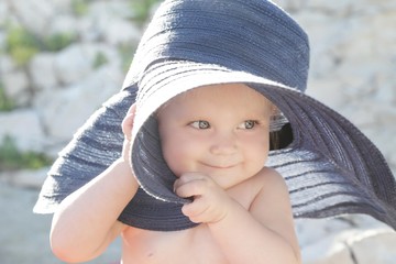 Close up portrait of an adorable baby girl wearing a blue wide-brimmed hat