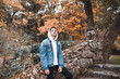 Stylish teenag boy 16-18 year old wearing white hoody with denim jacket posing outdoors. Looking at camera. 20s.