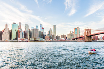 View of outside outdoors in NYC New York City Brooklyn Bridge Park by east river, cityscape skyline at day sunset, skyscrapers, buildings, motorboat, boat people