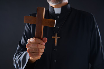 Priest holding cross of wood praying