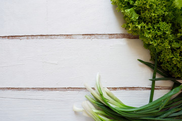 Frame of fresh onion, lettuce on a wooden white board. Useful recipes