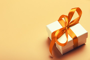 white gift box with orange bright ribbon on yellow background. beautiful gift for the new year, chri