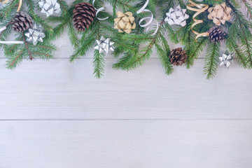 On a light wooden background copy space. Top composition of fir branches, decorative ribbons, bows and cones.