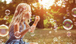 Leinwandbild Motiv Portrait of a cheerful girl blowing soap bubbles