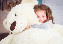 A Child Is Hugging A Big Teddy Bear. Happy Girl Hugging A Soft Toy.
