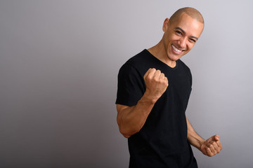 Handsome happy bald man smiling with arm raised