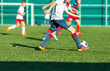 © Natali - football teams - boys in red, blue, white sportswear play soccer on the green field. boys dribbling. dribbling skills. Team game, training, active lifestyle, hobby, sport for kids concept