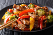 Stir-fried teriyaki beef with red and yellow bell pepper, broccoli and sesame seeds close-up on the table. horizontal