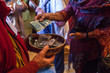 Woman with colorful clothes is putting 10 canadian dollars into a basket as voluntary contribution after a show - Closeup picture with a man in red shirt holding the basket