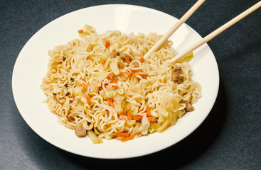 Instant noodles in white plate. Close-up.