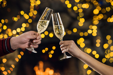 Couple clink champagne glasses at night on bright holiday