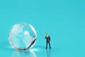 Miniature people: businessman standing on earth with blue background