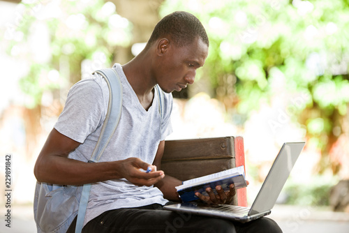 Fotografia young student man sitting in city working with laptop