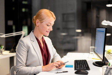 Poster - business, deadline and technology concept - businesswoman or bookkeeper with smartphone and computer working at night office