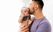 family, fatherhood and people concept - close up of happy father kissing little baby daughter