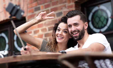 Poster - Happy cheerful couple sitting down at a cafe and making selfie