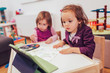 © Mediteraneo - Two adorable little sisters playing with a digital tablet at home.