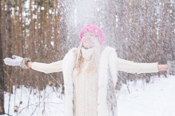 Happy young woman plays with a snow at snowy forest outdoor