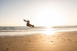 © Westend61 - Young man doing somersaults on the beach