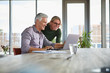 © Westend61 - Smiling mature couple using laptop on table at home