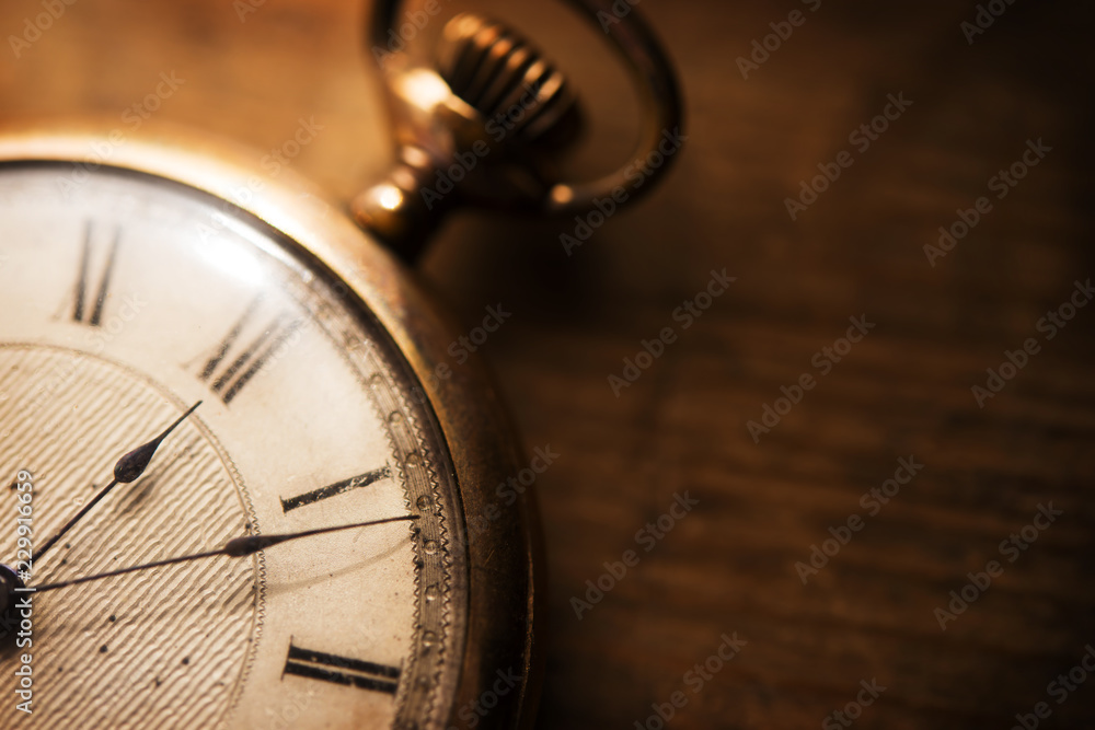 Old pocket watch on grungy wooden desk. Shot in low key and extremely shallow depth for impressional feel. Focus is on etching of clock face plate. - obrazy, fototapety, plakaty 