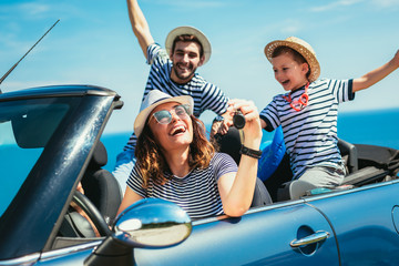 Happy family travel by car to the sea. People having fun in cabriolet. Summer vacation concept