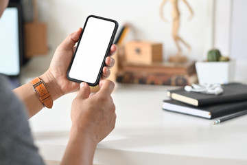 Closes-up male hand using mobile smart phone at desk workspace