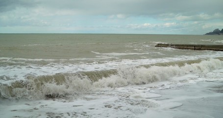 raging waves. Water from the river was mixed with sea water. Muddy water in the sea. Splashes from the waves bumping against the rocky shore