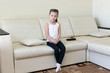 © ALEXEY - The little girl is sitting on the couch. Girl 5 years of age alone sitting in the room.