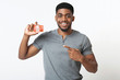 © Prostock-studio - Cheerful african-american man pointing at credit card