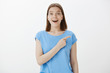 © Cookie Studio - Excited attractive female friend with fair hair, staring with popped eyes at camera, smiling broadly while pointing at upper right corner, mesmerized with amazing copy space, standing over grey wall
