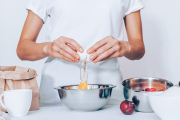 Woman wearing white t-shirt breaking raw egg