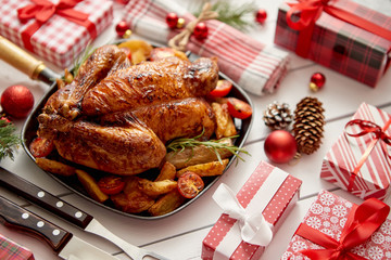 Roasted whole chicken or turkey served in iron pan with beautiful Christmas decoration. Placed on white rustical wooden background. Top view.