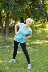 Wall Mural - Senior woman doing streching exercise in the park