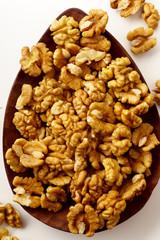 Close up overhead picture of raw walnuts on white background isolated on wooden tray