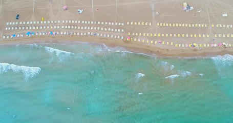Poster - Dreamland beach from aerial top view. Tourists relaxing and surfing, umbrellas and deck chairs on the beach. Aerial view of sandy beach with tourists swimming in beautiful clear sea water.