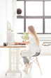 © xartproduction - Young business woman working at home behind a laptop. Creative Scandinavian style workspace